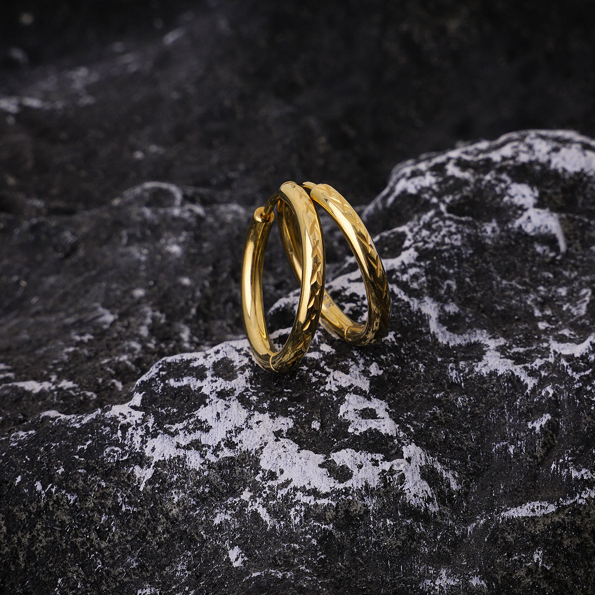 Gold hoop earrings on a textured black surface