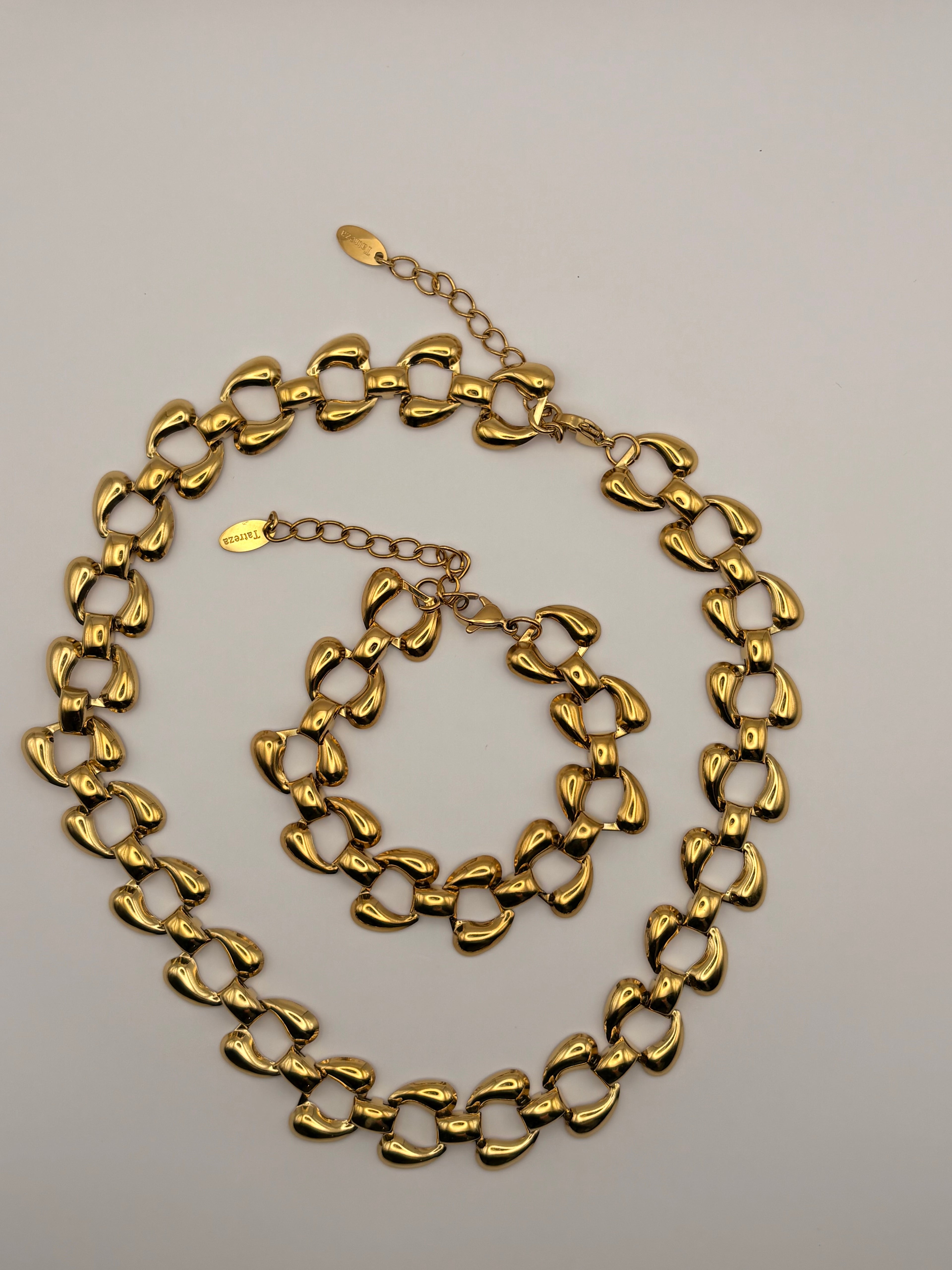A gold-toned chunky link chain necklace and matching bracelet displayed on a light gray background.