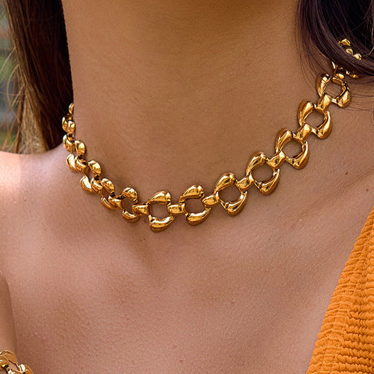Person wearing a gold chain necklace with a blurred background.