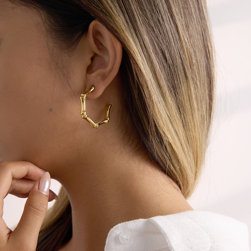 Gold hoop earring worn by a person with a neutral background