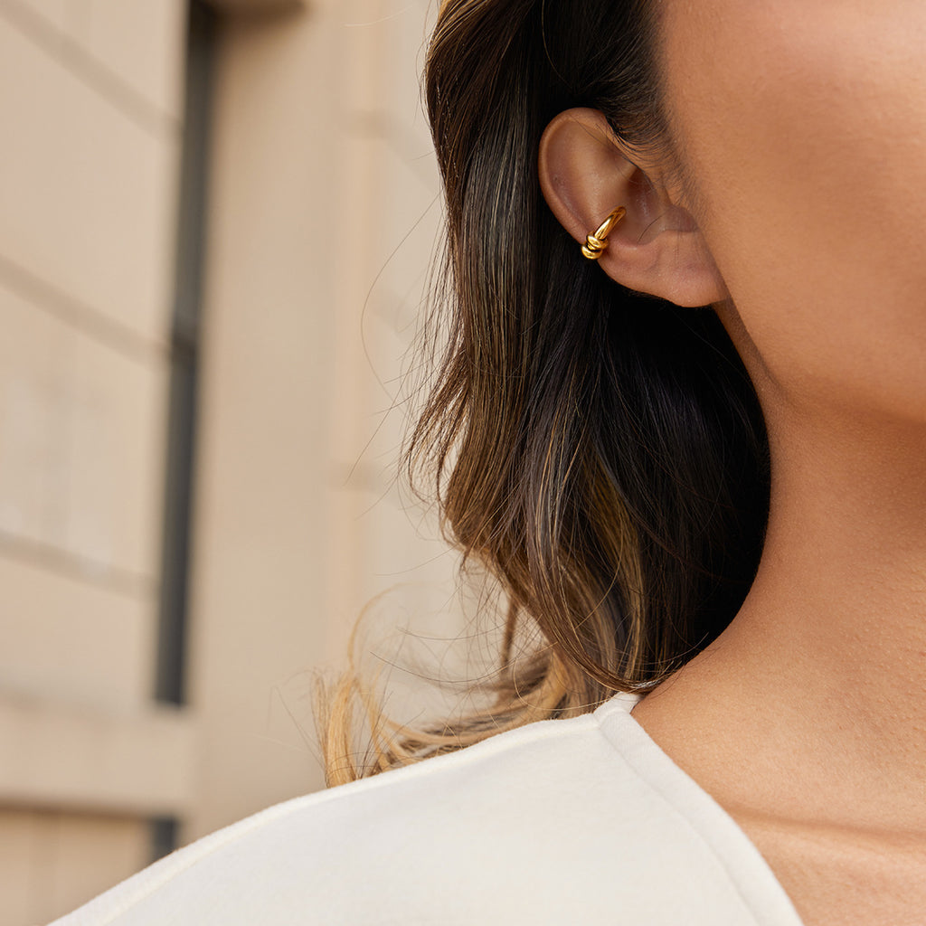 Close-up of a person wearing a gold earring with a blurred background