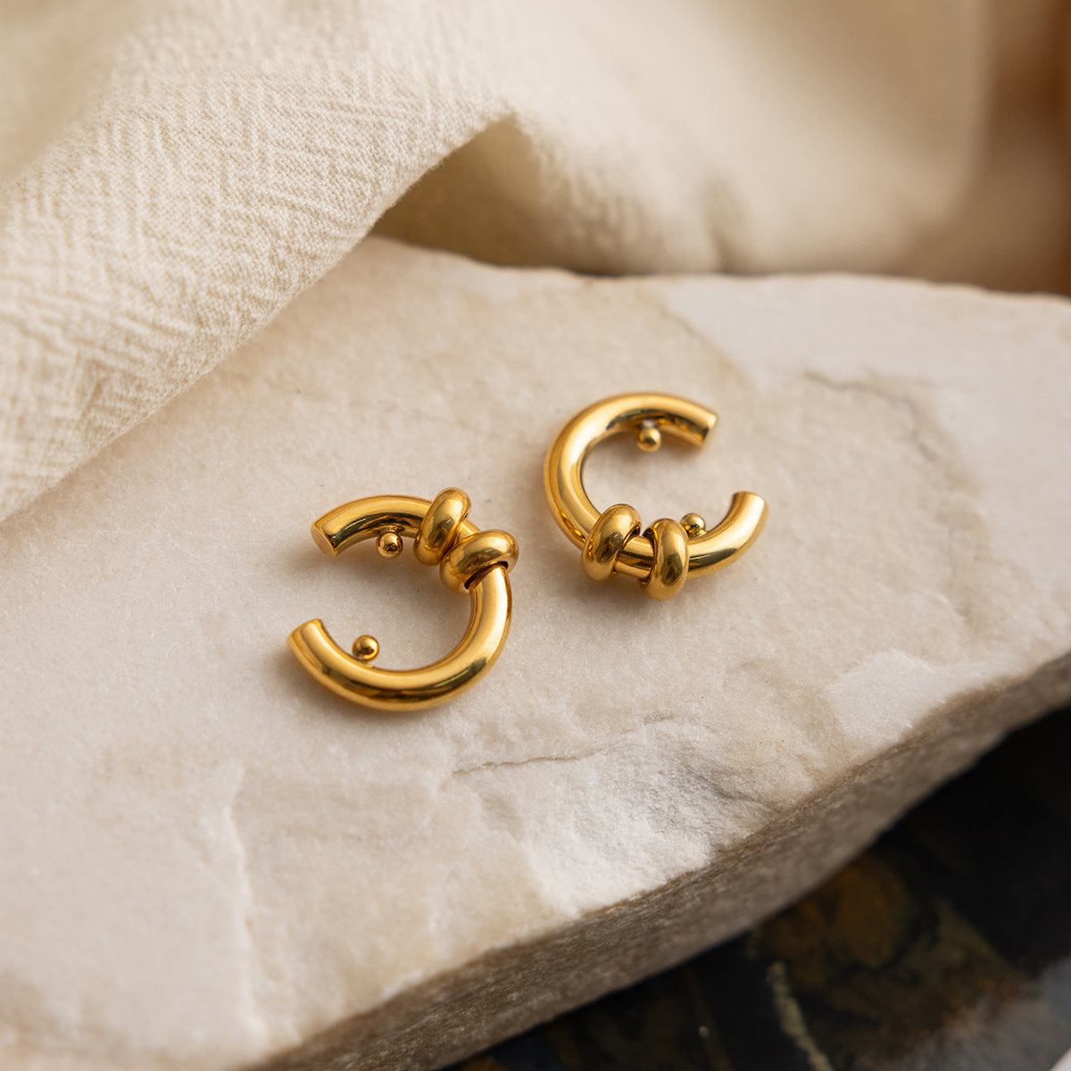 Gold hoop earrings on a textured beige surface